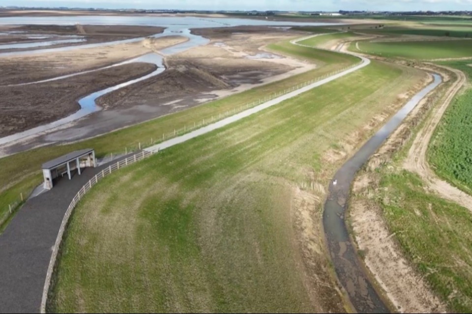 View of the new embankment with intertidal habitat in the background, and a bird hide near the eastern end of the scheme -  Environment Agency
