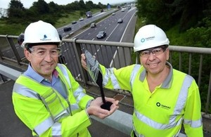 Martin Bolt, left, of Highways England and Paul Fleetham of Tarmac above the M1 in the East Midlands with some of the rubber granules being trialled in the road surface